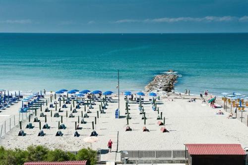 einen Strand mit Liegestühlen und Sonnenschirmen und dem Meer in der Unterkunft Hotel Rondine in Marinella di Sarzana