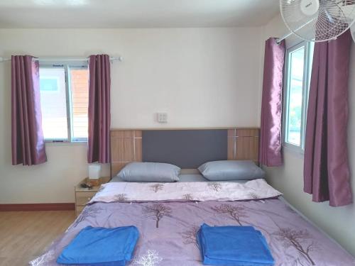 a bedroom with a bed with two blue pillows on it at Stay Ban Posai with Pool in Prakhon Chai