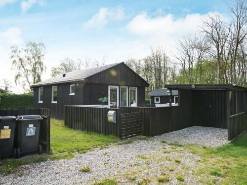 una casa negra con una valla y dos cubos de basura en 6 person holiday home in Odder, en Odder