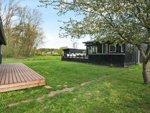 een zwart huis in een tuin met een houten terras bij 6 person holiday home in Odder in Odder