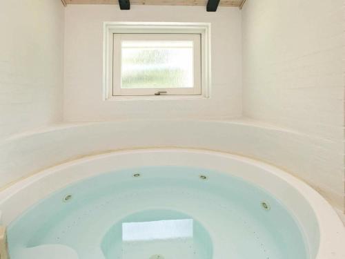 Cette chambre dispose d'une baignoire et d'une fenêtre. dans l'établissement 8 person holiday home in Bl vand, à Blåvand