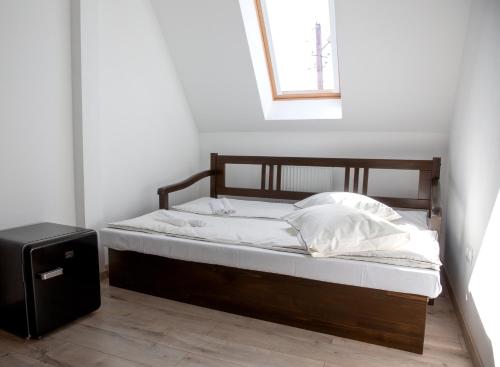 a bed with a wooden frame and white sheets and pillows at Csató Panzió - Pensiunea Csató in Joseni