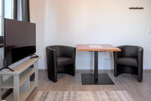 an office with two chairs and a table and a television at Csató Panzió - Pensiunea Csató in Joseni