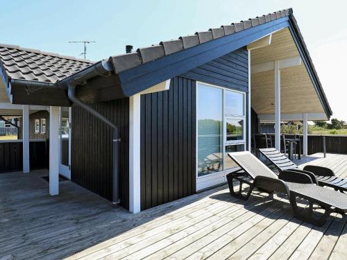 a wooden deck with two chairs and a house at 6 person holiday home in Ringk bing in Søndervig