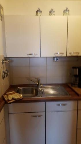 eine Küche mit einem Waschbecken und weißen Schränken in der Unterkunft Ferienwohnung FRIADO im Ferienpark Oberallgäu in Missen-Wilhams