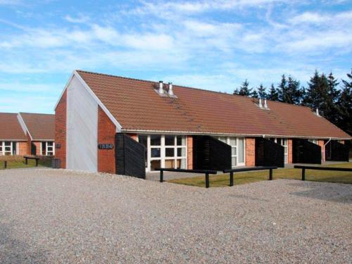 a red and white building with a brown roof at Grand holiday home- Type 11 in Blåvand