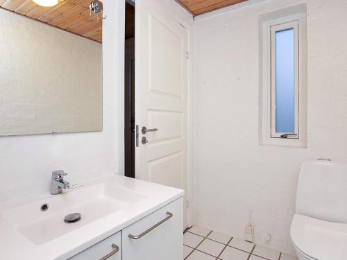a white bathroom with a sink and a mirror at Grand holiday home- Type 11 in Blåvand