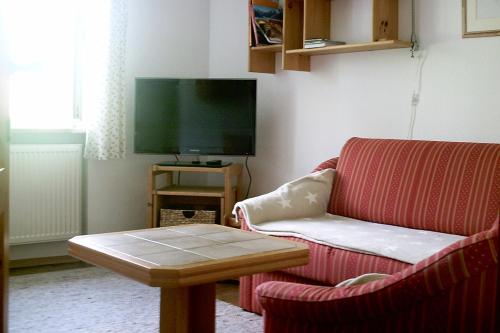 uma sala de estar com um sofá vermelho e uma televisão em Haus Fichteneck em Berchtesgaden