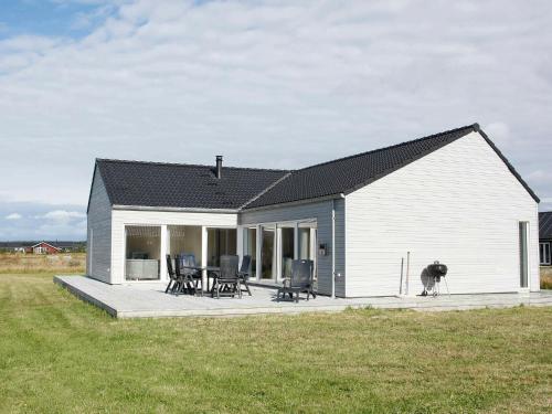 Casa blanca pequeña con terraza y sillas en 10 person holiday home in Brovst, en Brovst