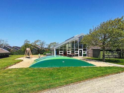 a building with a green circle in front of a playground at 6 person holiday home on a holiday park in Hemmet in Hemmet