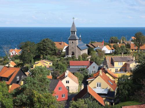 a small town with a church and the ocean at 5 person holiday home on a holiday park in Gudhjem in Gudhjem