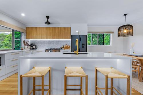 una cocina con una gran isla blanca con taburetes de bar en Airlie Abode en Airlie Beach