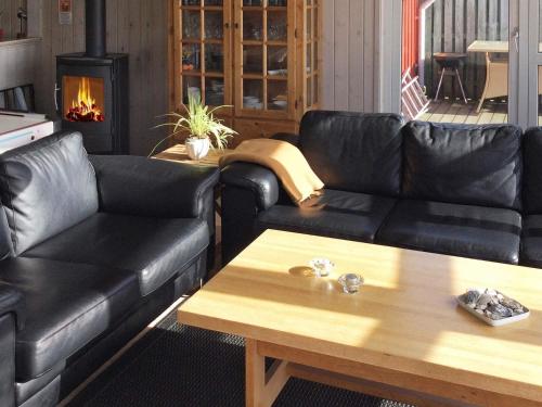 ロンストラップにある6 person holiday home in Hj rringのリビングルーム(黒い革張りのソファ、コーヒーテーブル付)