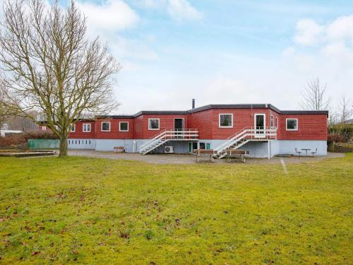 un gran edificio rojo con un árbol en un campo en 30 person holiday home in Nordborg, en Nordborg