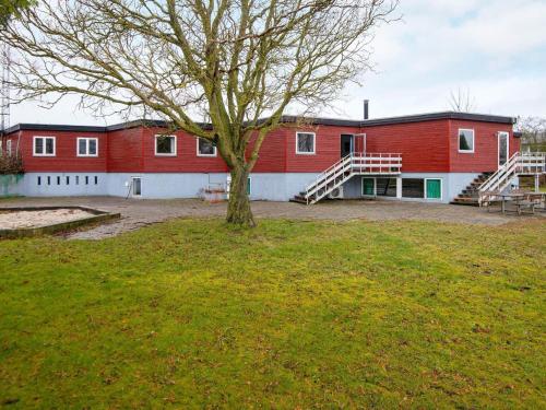 un grande edificio rosso con un albero nel cortile di 30 person holiday home in Nordborg a Nordborg