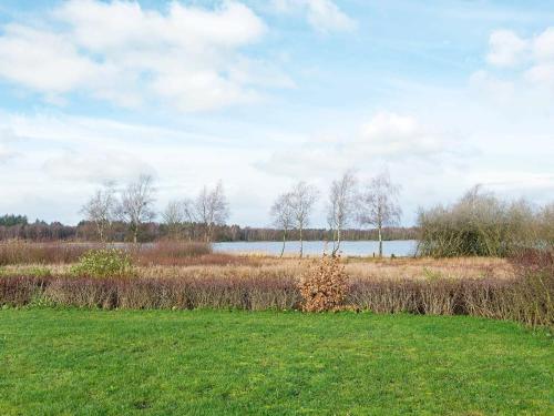 ein Grasfeld mit einem See im Hintergrund in der Unterkunft 10 person holiday home in Ansager in Ansager