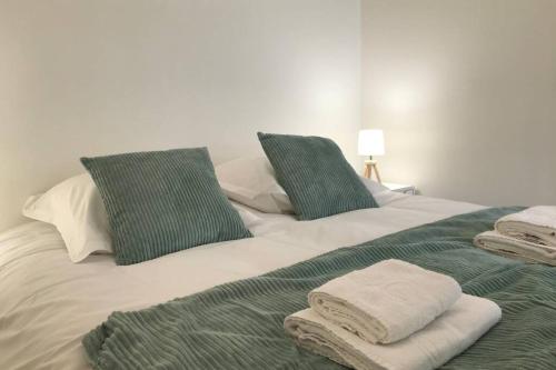 - un lit blanc avec des oreillers et des serviettes verts dans l'établissement LES JARDINS - terrasse & jardin au calme, à Annecy