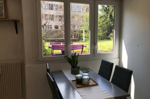 une table à manger avec des chaises et une fenêtre dans l'établissement LES JARDINS - terrasse & jardin au calme, à Annecy