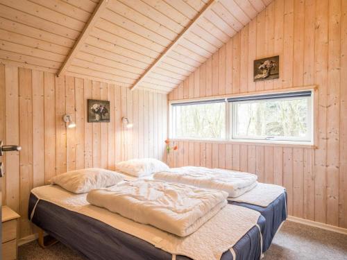 two beds in a room with wooden walls and a window at 7 person holiday home in Oksbøl in Oksbøl