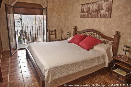 a bedroom with a bed with red pillows on it at Casa Rural Castillo Diempures in Cantalojas