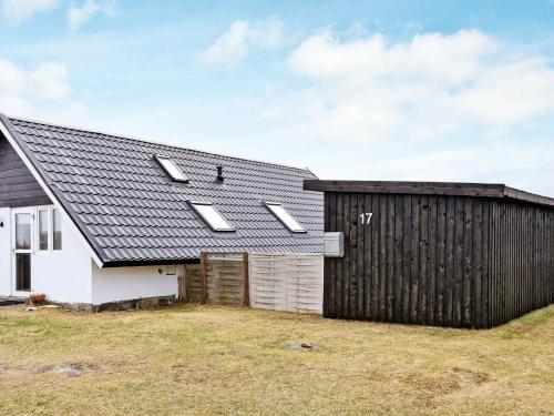 a house with a black roof and a fence at 6 person holiday home in Harbo re in Harboør