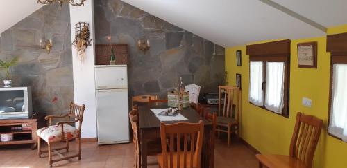 Una cocina con refrigerador y una mesa con sillas. en Casa Antonio y Benina, en Sosas de Laciana