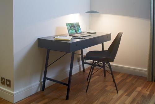 a desk with a laptop on it with a chair at Cheval Harrington Court at South Kensington in London