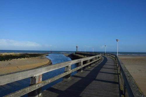 a wooden bridge over a beach with water at Studio 24 - Coucher de Soleil & Vue Mer in Courseulles-sur-Mer