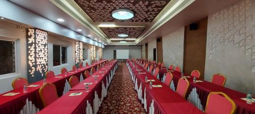 a banquet hall with red tables and red chairs at Lee-Benz ARK HOTEL in Kumbakonam