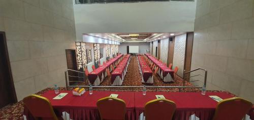 a long banquet hall with red tables and chairs at Lee-Benz ARK HOTEL in Kumbakonam