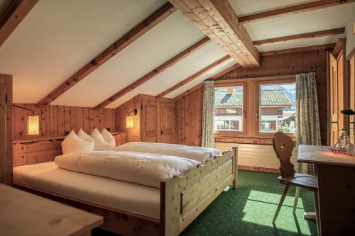 a bedroom with a bed and a large window at Hotel Wynegg in Klosters