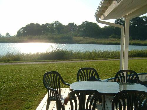 a table and chairs sitting on a porch next to a lake at 6 person holiday home in Otterndorf in Otterndorf