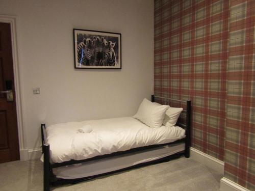 a small bed with white sheets and pillows in a room at The Craigie Hotel in Penicuik