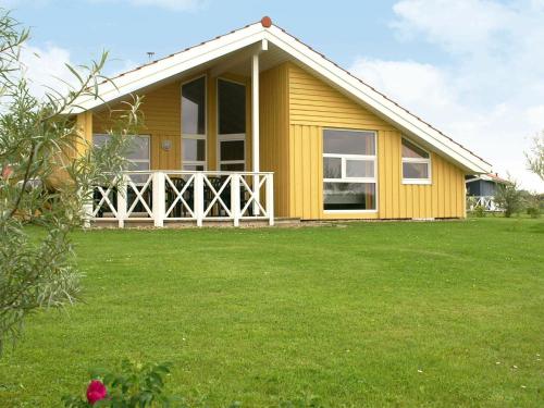 a yellow house with a green lawn in front of it at 12 person holiday home in Otterndorf in Otterndorf