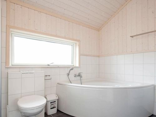 ein Bad mit einer Badewanne, einem WC und einem Fenster in der Unterkunft 10 person holiday home in Gro enbrode in Großenbrode