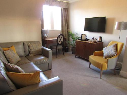 a living room with a couch and a flat screen tv at The Craigie Hotel in Penicuik