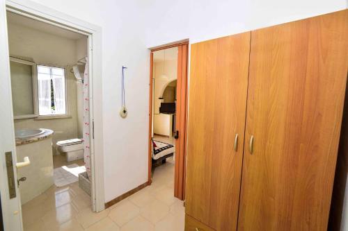 a bathroom with a toilet and a wooden cabinet at SOLEMAREPONZA Casa Bougainvillea in Ponza