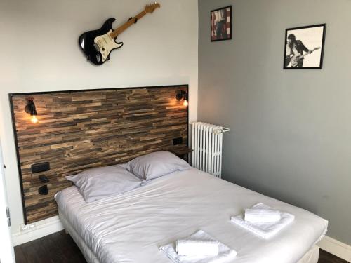 Ce lit se trouve dans un dortoir doté d'une guitare sur le mur. dans l'établissement Hôtel Renova, à Nantes