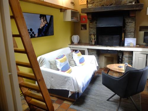 a living room with a white couch and a kitchen at Le Fournil Gîte Rural in Trois-Ponts