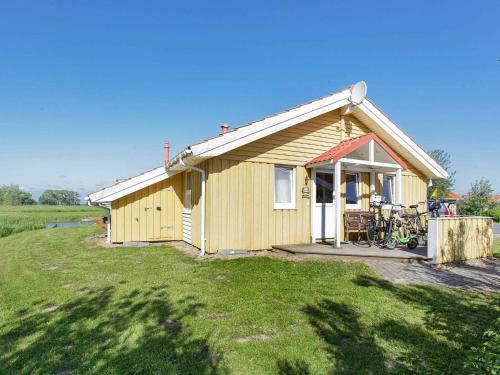 mały żółty dom z rowerem zaparkowanym przed nim w obiekcie 12 person holiday home in Otterndorf w mieście Otterndorf