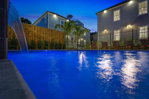 a blue swimming pool in front of a house at Hosteeva Modern Condo Near Magazine St & Close to FQ in New Orleans