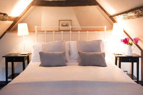 uma cama com lençóis brancos e almofadas num quarto em The Ram Inn em Lewes