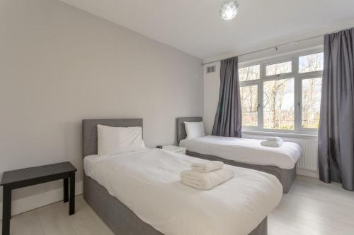 ロンドンにあるModern 2 Bedroom Apartment in Mordenのベッド2台と窓が備わるホテルルームです。