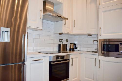 a kitchen with white cabinets and a stainless steel refrigerator at Beautiful 2 Bedroom Ballsbridge Apartment near the Aviva in Dublin
