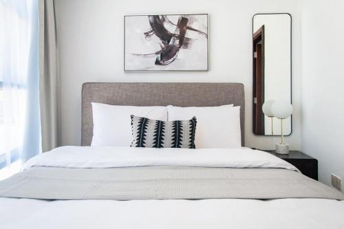 a bedroom with a white bed with two black and white pillows at Sophisticated 2 Bedroom with Lush Interiors in JVC in Dubai