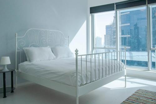 a white bed in a room with a large window at Cozy 1 Bedroom with Dubai Eye and sea views minutes to beach in Dubai