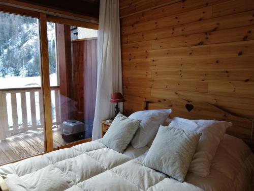 a bedroom with a white bed with a wooden wall at La Godille in Pra-Loup