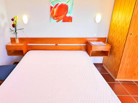 a bedroom with a large white bed in a room at Parque de Campismo da Ilha do Pessegueiro in Porto Covo