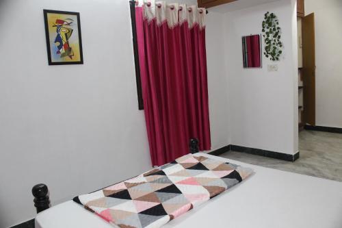 a bedroom with a checkeredkered bed in front of a red curtain at FriendlyStay at Madanandapuram in Chennai
