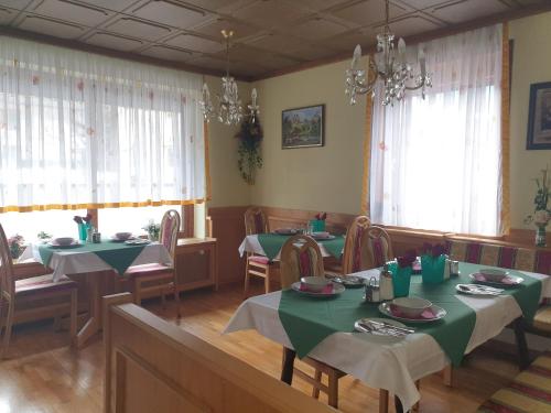 ein Esszimmer mit grünen Tischen, Stühlen und Fenstern in der Unterkunft Haus Elena in Lainach